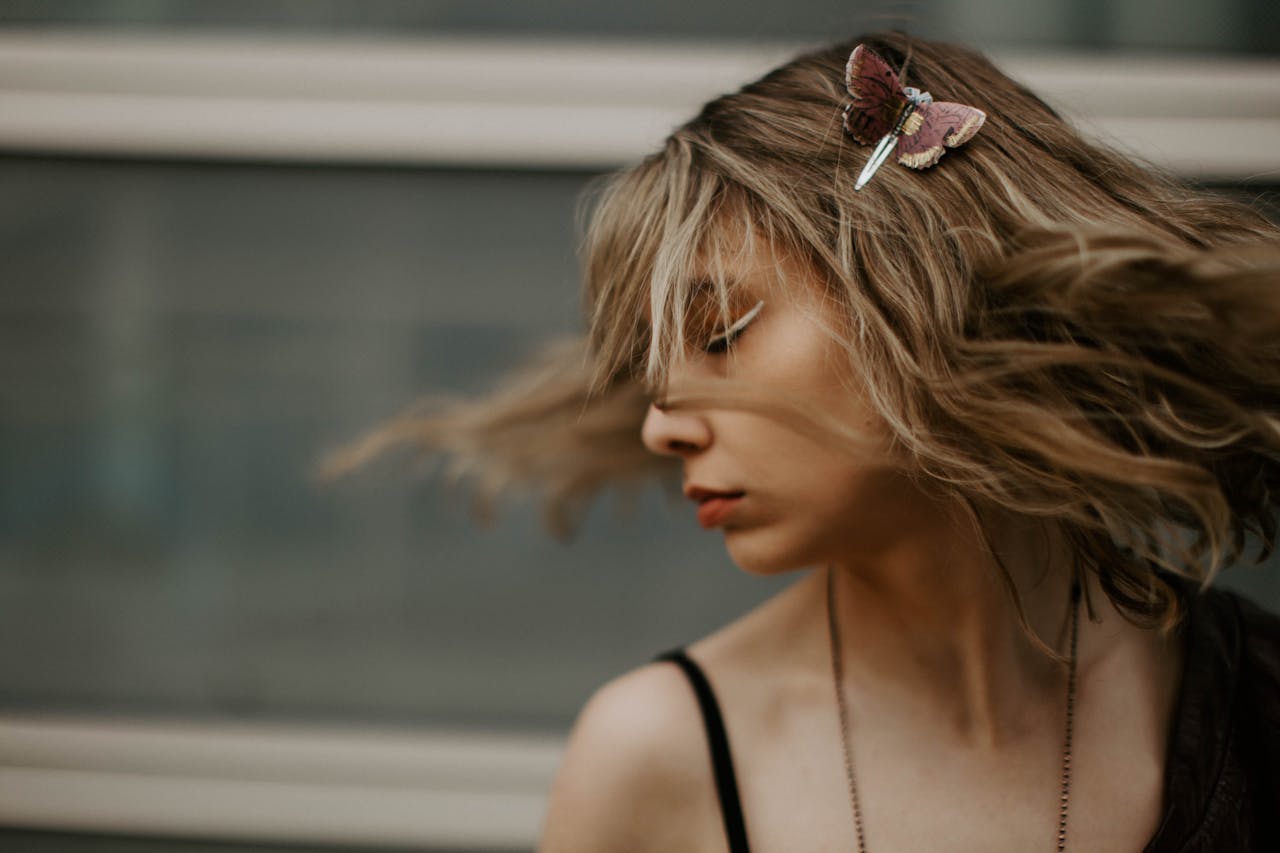 Artistic portrait of a woman with hair in motion and a butterfly clip, capturing style and motion.
